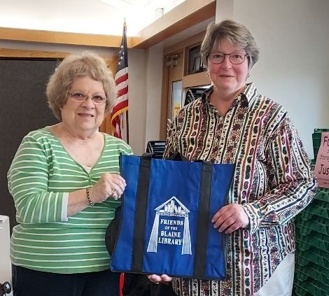 Pat Kingshott presenting our new book bag, featuring the new logo, to Ruth Lauman as a 'thank you' for her donation of her time to the project.  