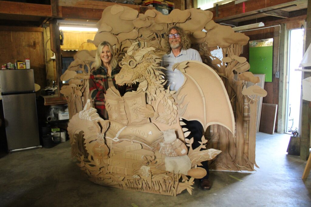 cardboard dragon sculpture with artist and interviewer