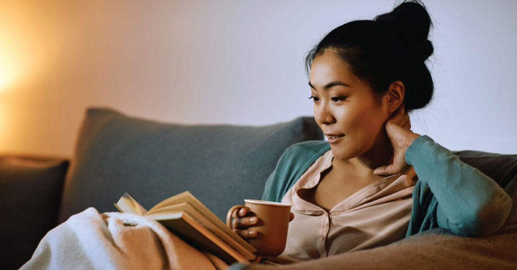 Woman reading a book and drinking a cup of tea